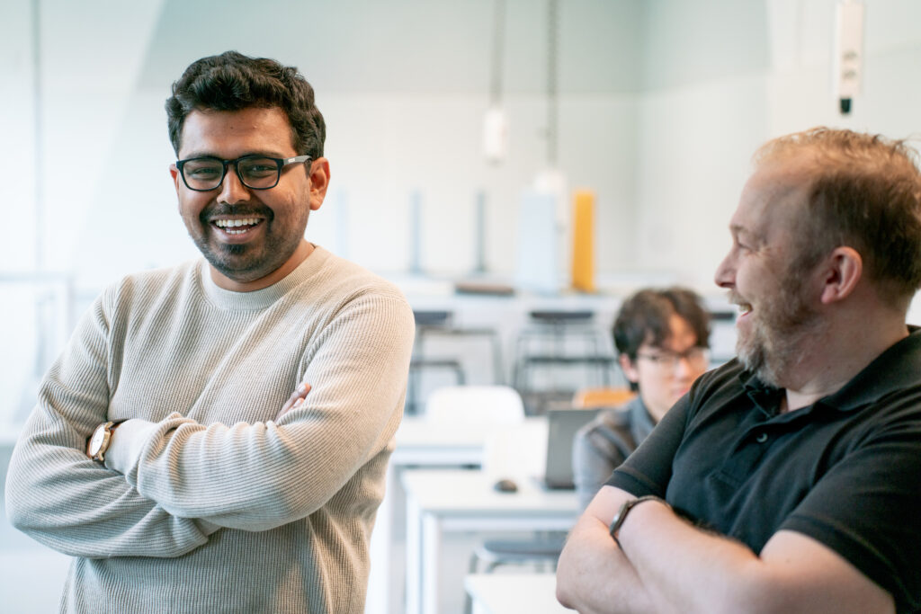 Two colleagues laughing in a classroom environment.